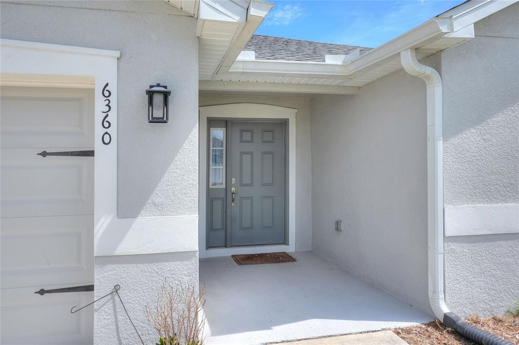 The exterior of a house features a gray front door, a side light, and a garage — 6360 GARDNER DRIVE, LAKELAND, FL