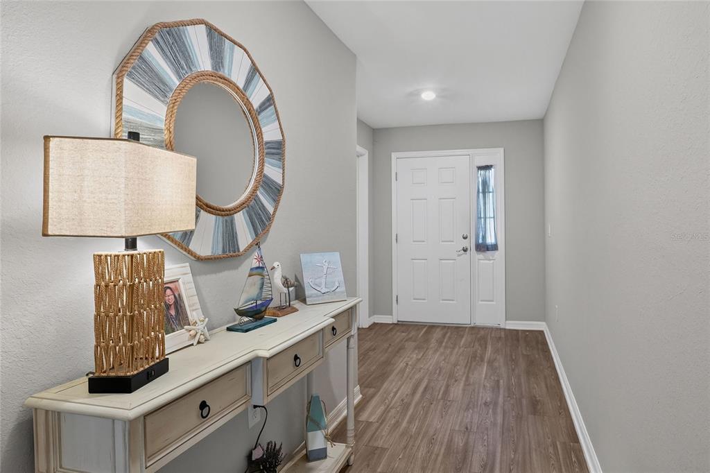 A foyer features a console table, a decorative mirror, and a white front door — 6360 GARDNER DRIVE, LAKELAND, FL