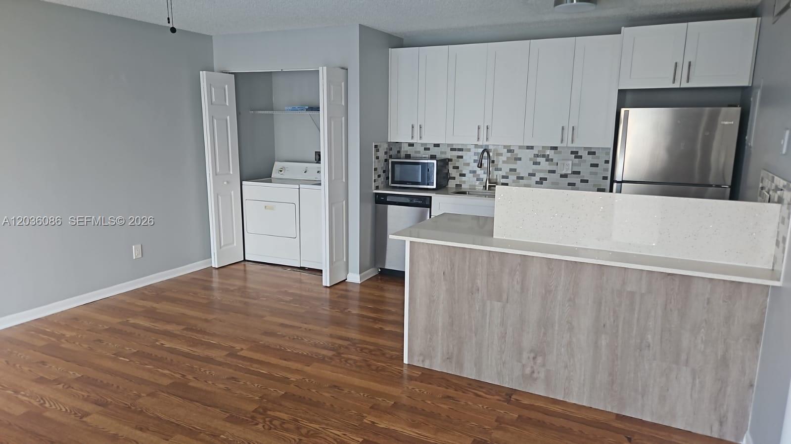 A kitchen with white cabinets, stainless steel appliances, and a wood-look island counter — WEST PALM BEACH, FL