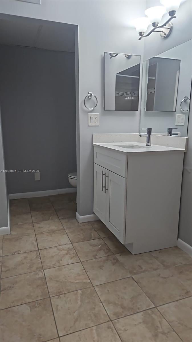 A bathroom features a white vanity, a mirror, a light fixture, and tiled flooring — WEST PALM BEACH, FL