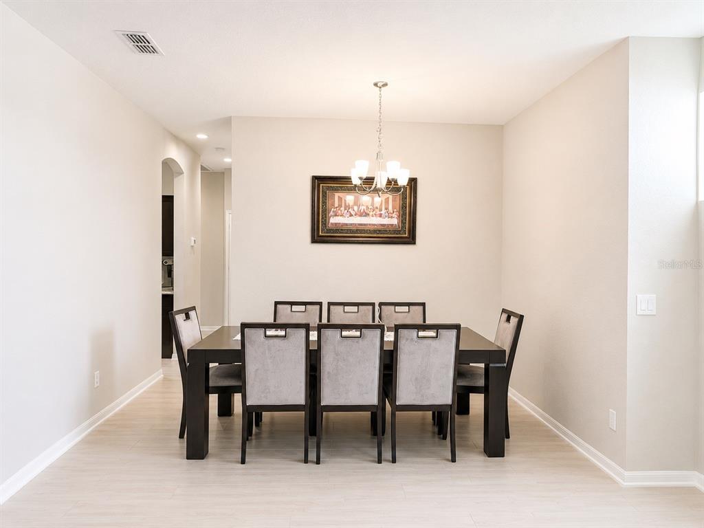 A dining room features a dark wood table with six upholstered chairs and a chandelier — 4539 CALUMET DRIVE, ST CLOUD, FL