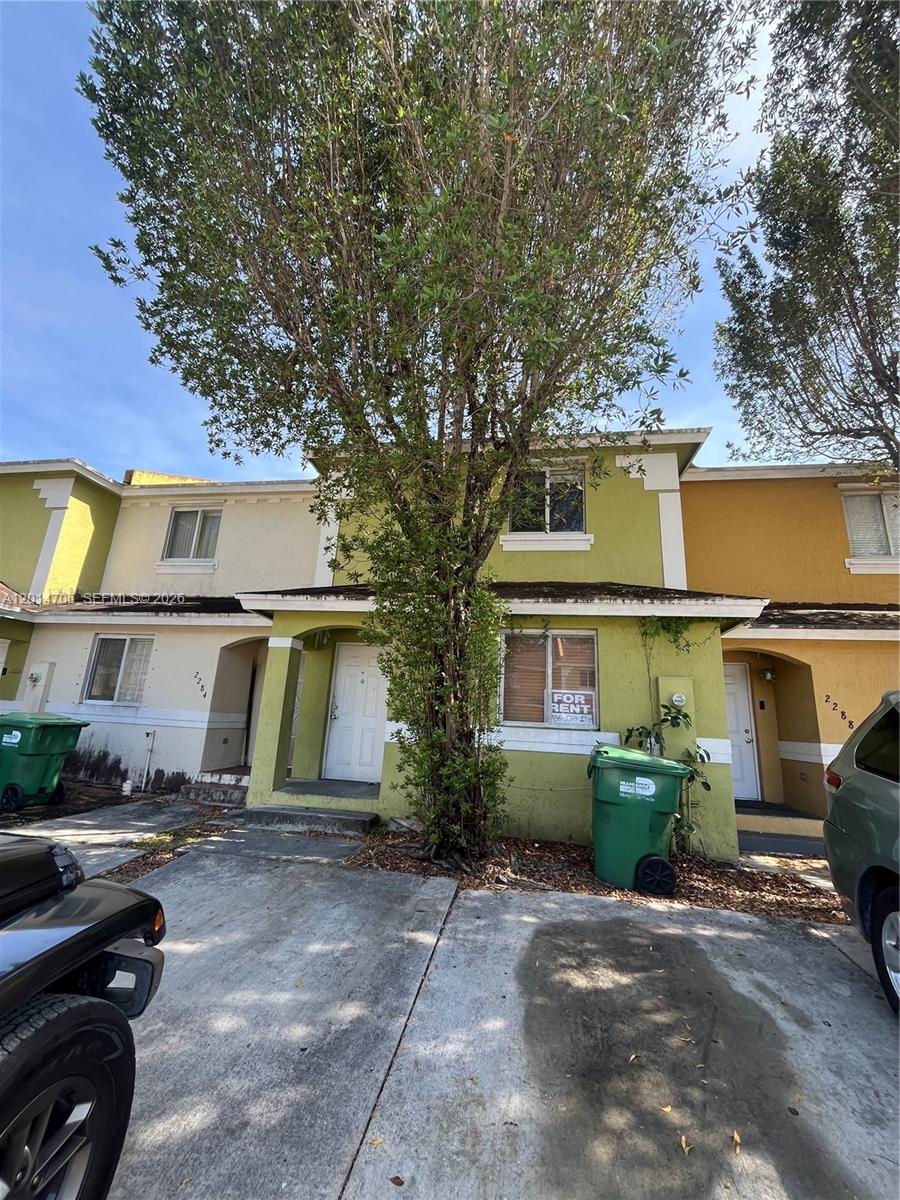 A two-story townhouse with a green exterior, a front tree, and a for-rent sign — 2286 NW 136th Ter # 0, Opa-Locka FL 33054, OPA-LOCKA, FL