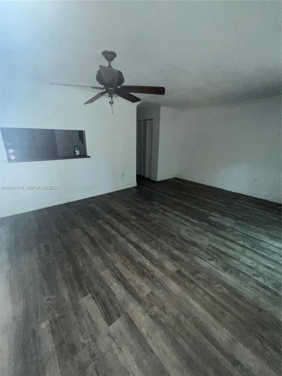 This living room features dark wood-look flooring, white walls, and a ceiling fan — 2286 NW 136th Ter # 0, Opa-Locka FL 33054, OPA-LOCKA, FL