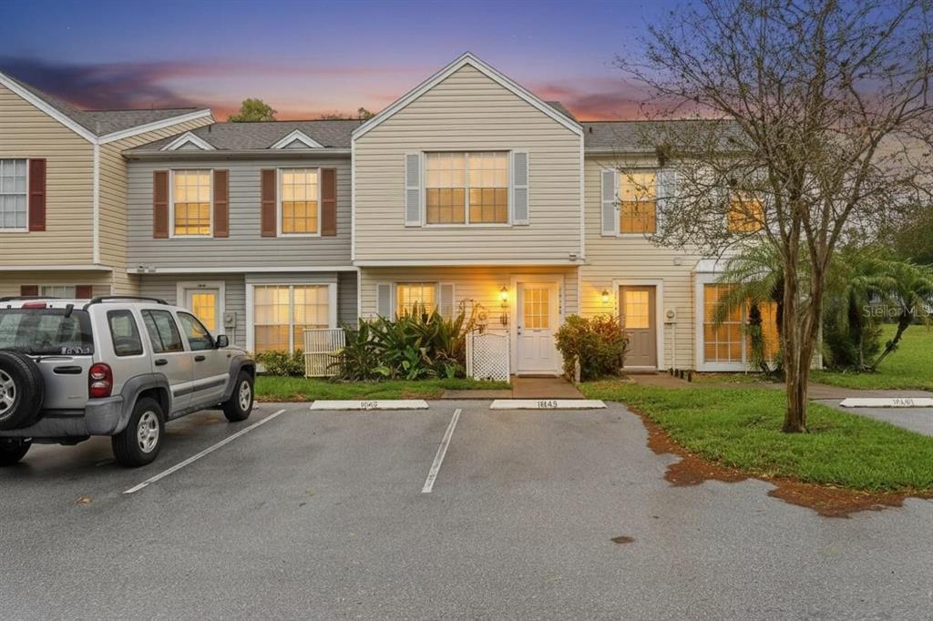 A two-story townhouse exterior with beige siding, a parking lot, and a silver SUV — 16143 RAMBLING VINE DRIVE E, TAMPA, FL