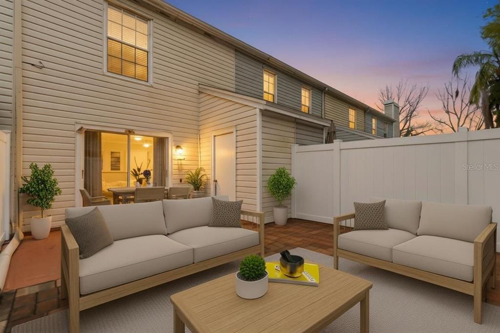 A patio with two outdoor sofas and a coffee table sits outside a beige townhouse — 16143 RAMBLING VINE DRIVE E, TAMPA, FL