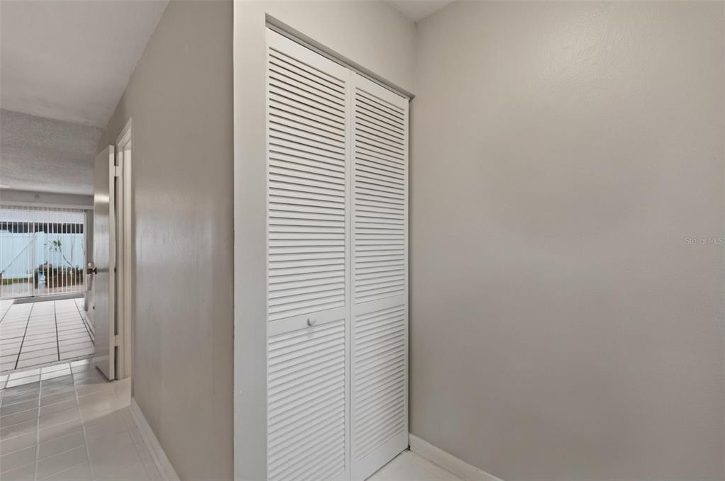 A hallway features white louvered closet doors and light-colored tile flooring — 16143 RAMBLING VINE DRIVE E, TAMPA, FL