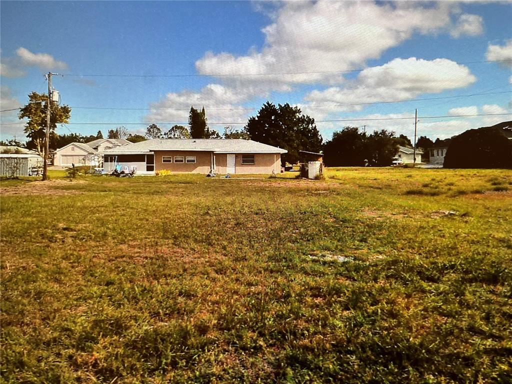 A wide, grassy lot features a single-story house with a light-colored exterior and roof — LOT 16 SAN RAFAEL AVENUE, NORTH PORT, FL
