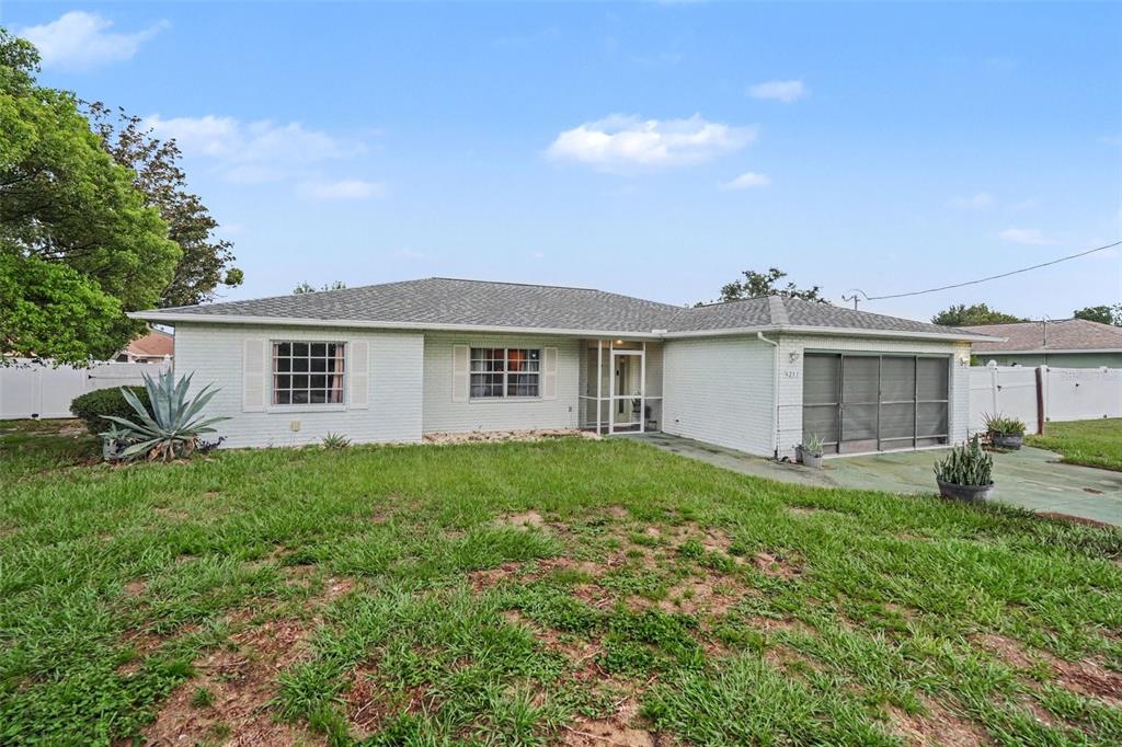 A single-story house with white brick siding, a screened-in porch, and a front lawn — 4233 DRISTOL AVENUE, SPRING HILL, FL