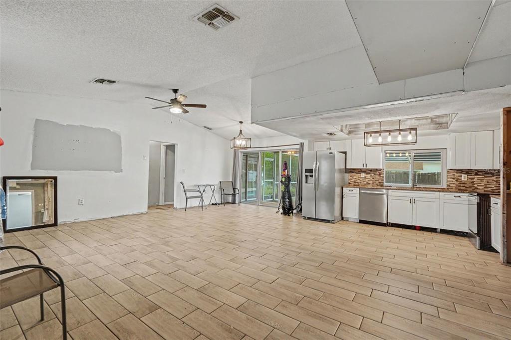 An open-concept kitchen and living area features white cabinetry, stainless steel appliances, and tile flooring — 4233 DRISTOL AVENUE, SPRING HILL, FL