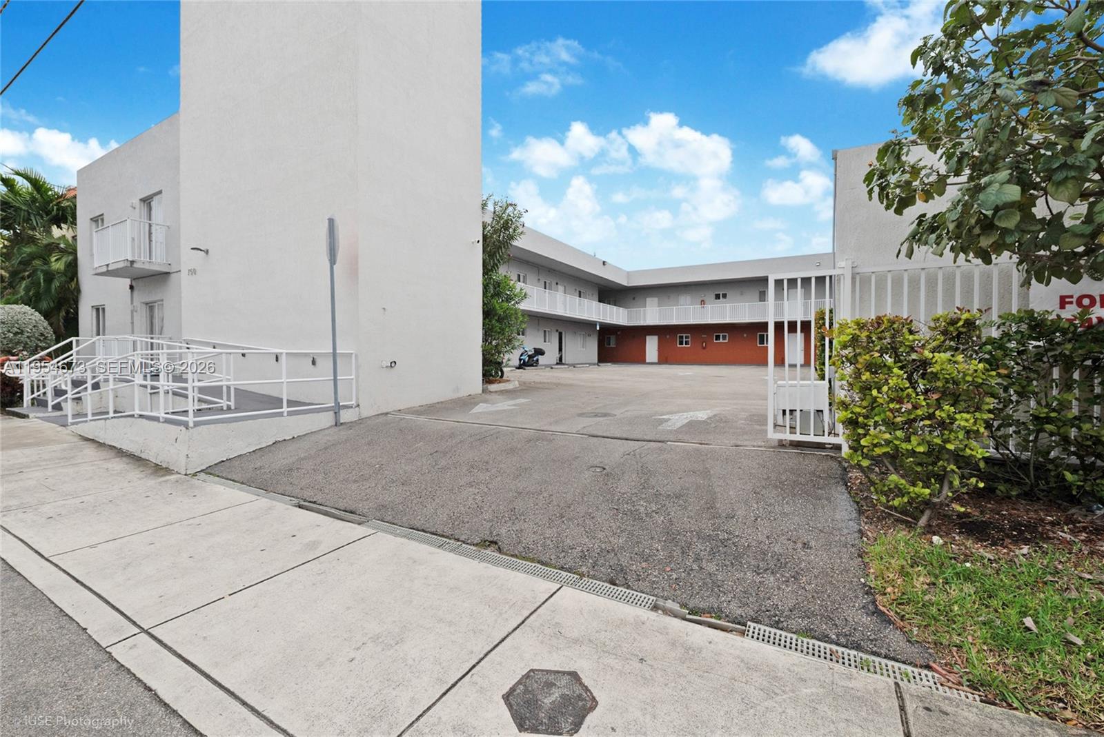 An exterior view of a two-story apartment building with a paved parking lot and ramp — 750 SW 2nd St, Miami FL 33130, MIAMI, FL