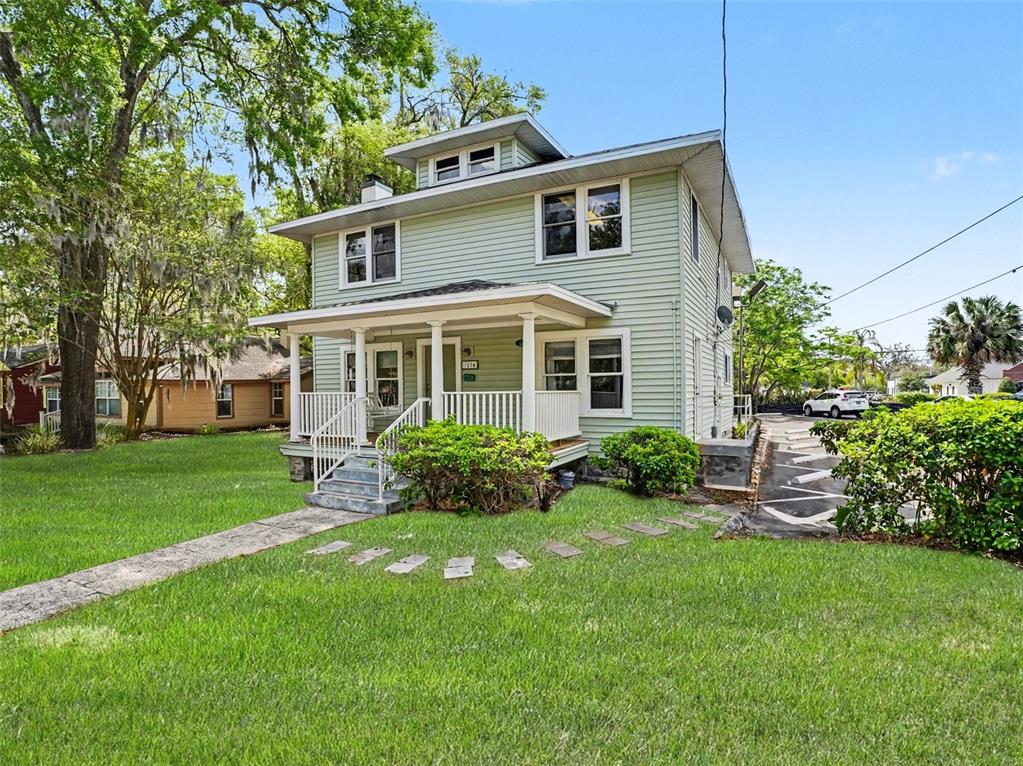 A two-story, light green house with a front porch and a grassy yard — 1214 E LIVINGSTON STREET STREET, ORLANDO, FL