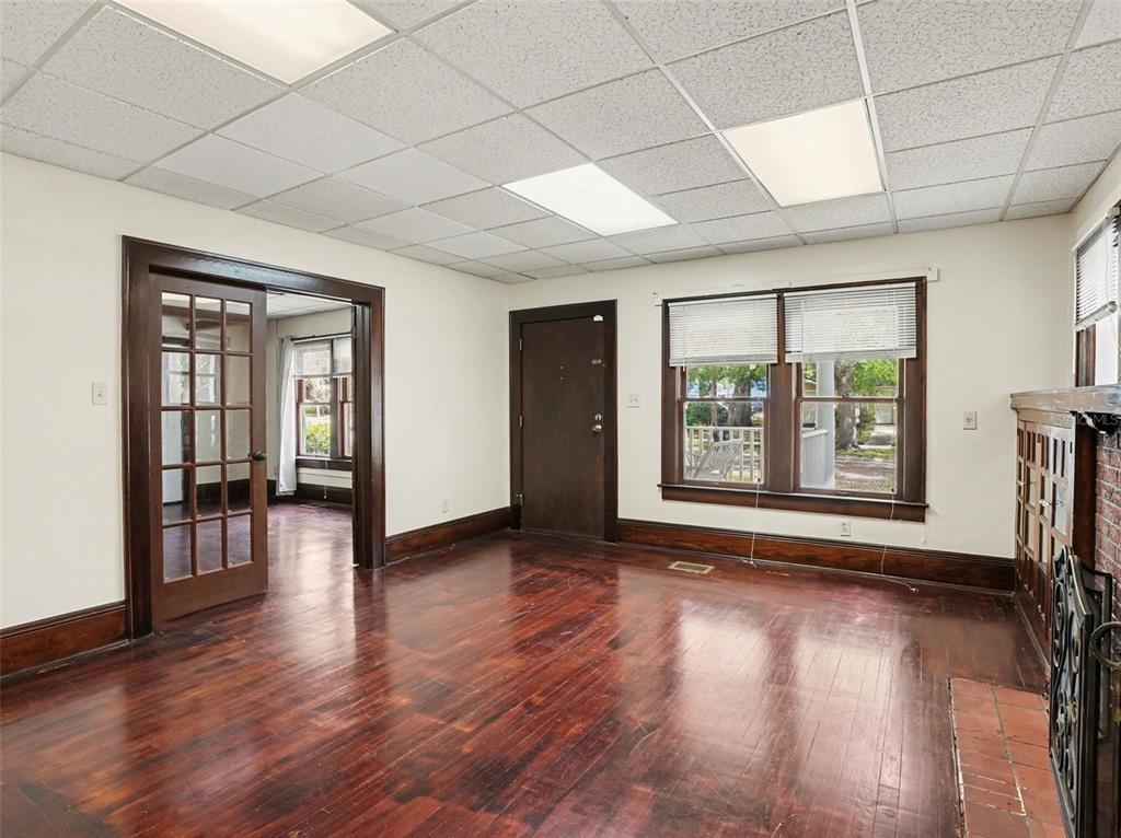 An interior room with dark wood floors, a drop ceiling, and a brick fireplace — 1214 E LIVINGSTON STREET STREET, ORLANDO, FL