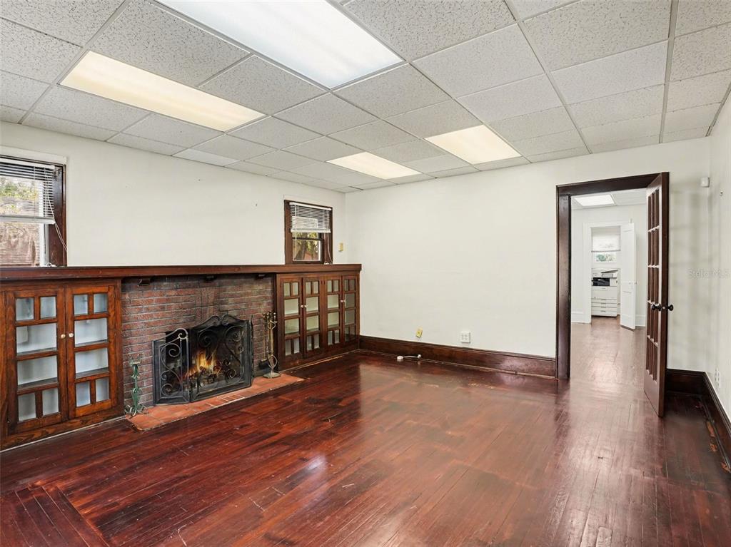 A room with hardwood floors, a brick fireplace, built-in wooden cabinets, and a drop ceiling — 1214 E LIVINGSTON STREET STREET, ORLANDO, FL