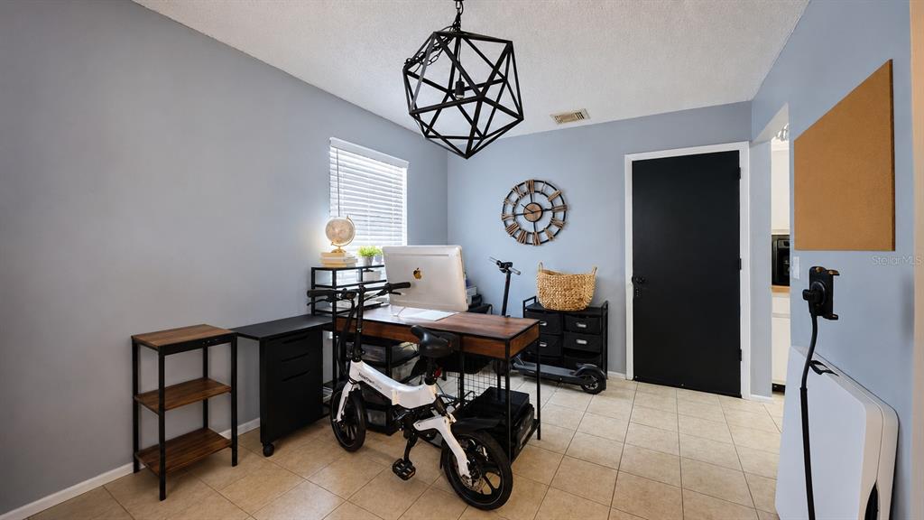 A home office features a desk, a folding bike, a black door, and a geometric chandelier — 257 CLEMENS COURT, ORLANDO, FL