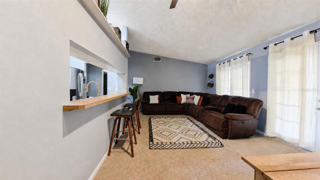 A living room features a brown sectional sofa, a patterned rug, and a breakfast bar — 257 CLEMENS COURT, ORLANDO, FL