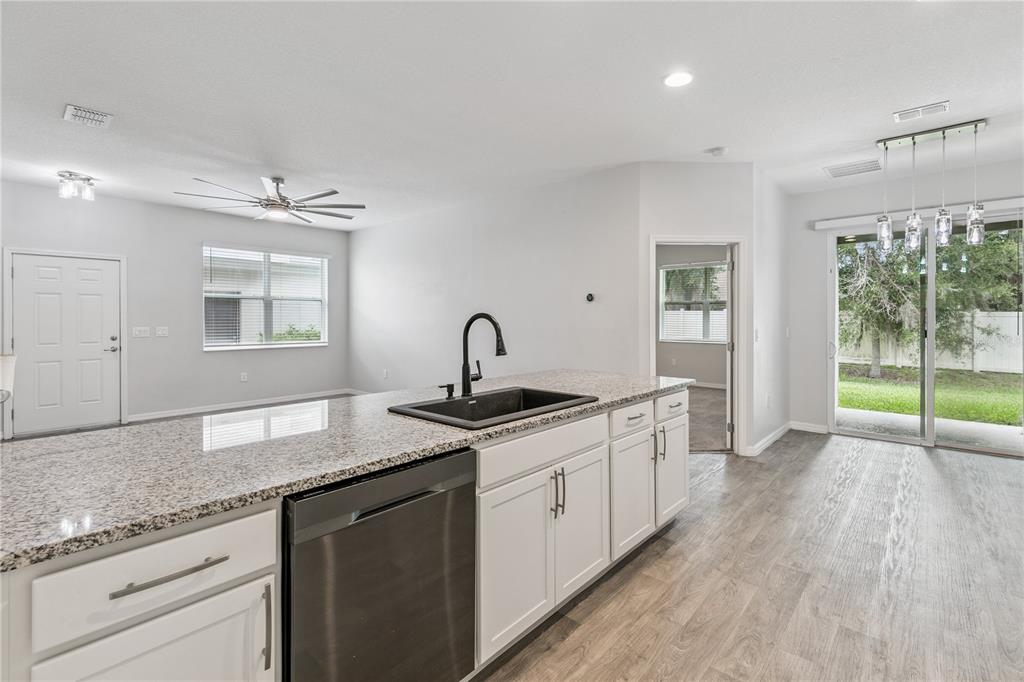 A kitchen island with a granite countertop and black sink overlooks an open living area — 1863 SHUMARD AVENUE UNIT 1863, ST CLOUD, FL