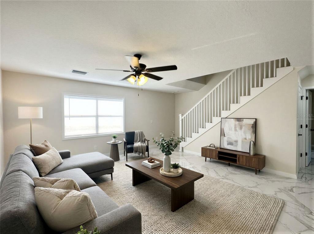 A living room features a grey sectional sofa, a wooden coffee table, and a staircase — 1133 OLYMPIC COURT, APOPKA, FL