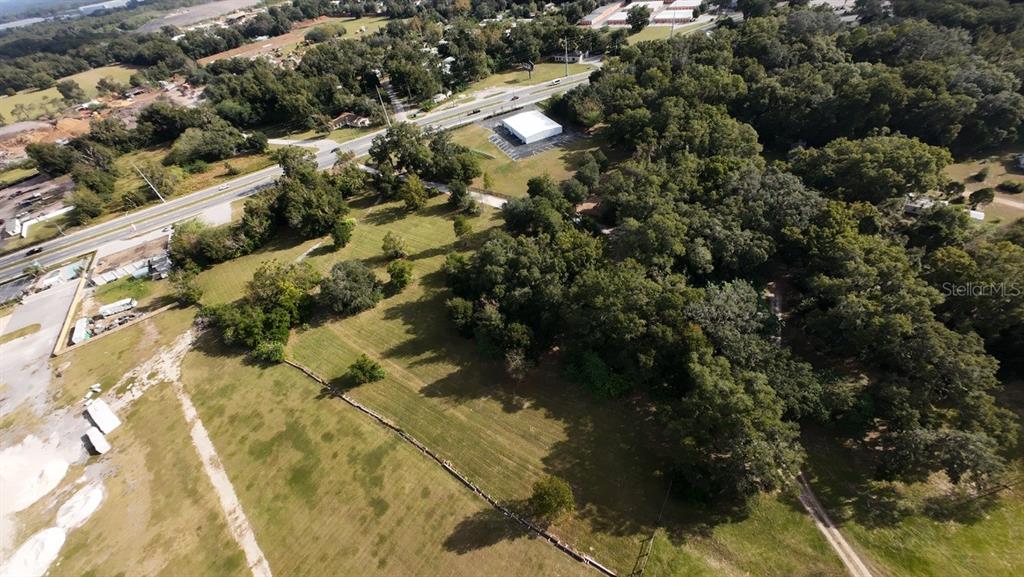 An aerial view shows a large, grassy lot bordered by trees and a paved road — 3308 NW BLITCHTON ROAD, OCALA, FL