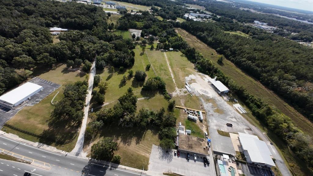 An aerial view shows multiple commercial buildings, a large grassy lot, and a paved road — 3308 NW BLITCHTON ROAD, OCALA, FL