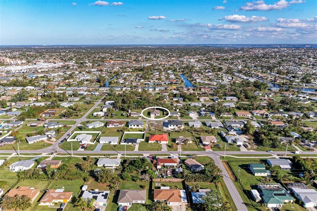 An aerial view shows a residential neighborhood with a single house circled in white — 3332 ELKCAM BOULEVARD, PORT CHARLOTTE, FL