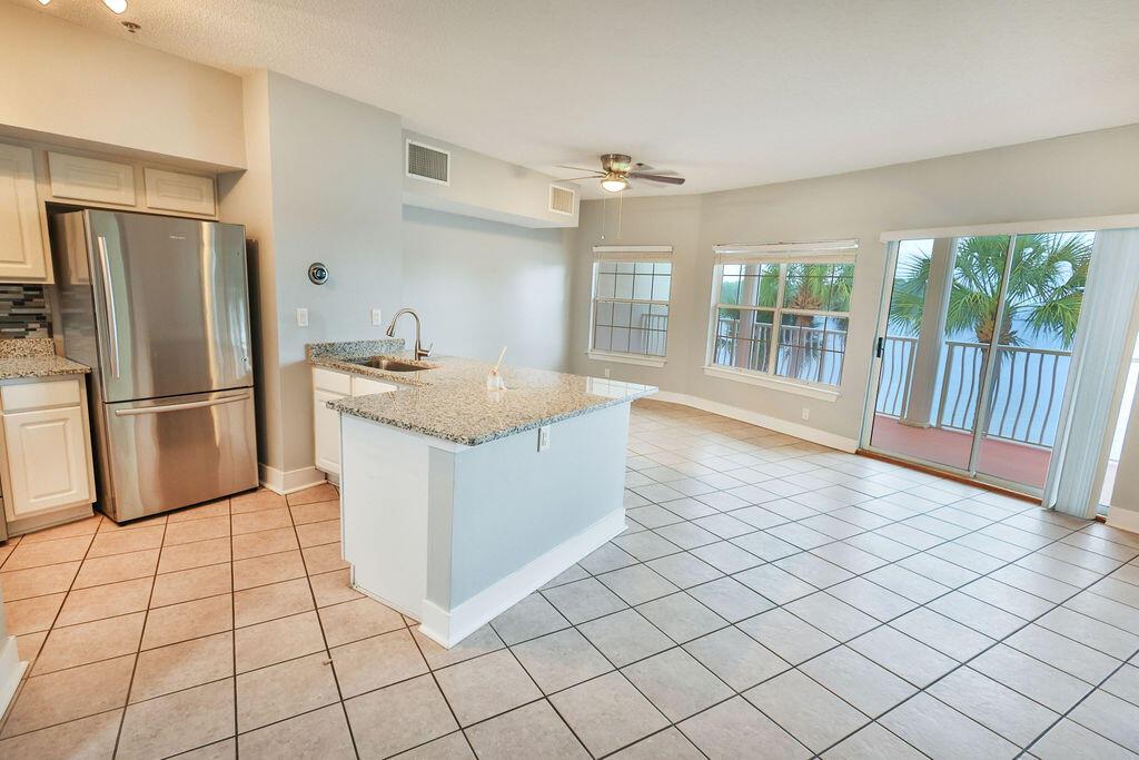 A kitchen with granite countertops and stainless steel appliances opens to a tiled living area — 5 Laguna Street # 205, FL 32548, FL