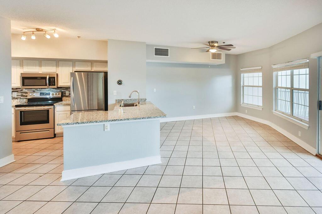 A kitchen with stainless steel appliances and granite countertops opens into a tiled living area — 5 Laguna Street # 205, FL 32548, FL
