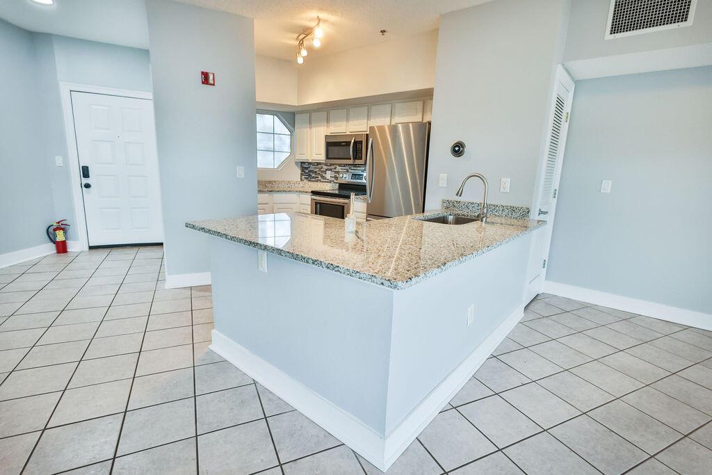 A kitchen with granite countertops, stainless steel appliances, and light blue walls over tile flooring — 5 Laguna Street # 205, FL 32548, FL