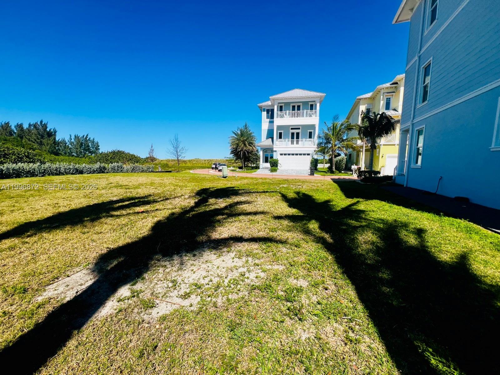 A grassy lot sits in front of a multi-story light blue house under a clear sky — 4803 Watersong Way, Fort Pierce FL 34949, FORT PIERCE, FL