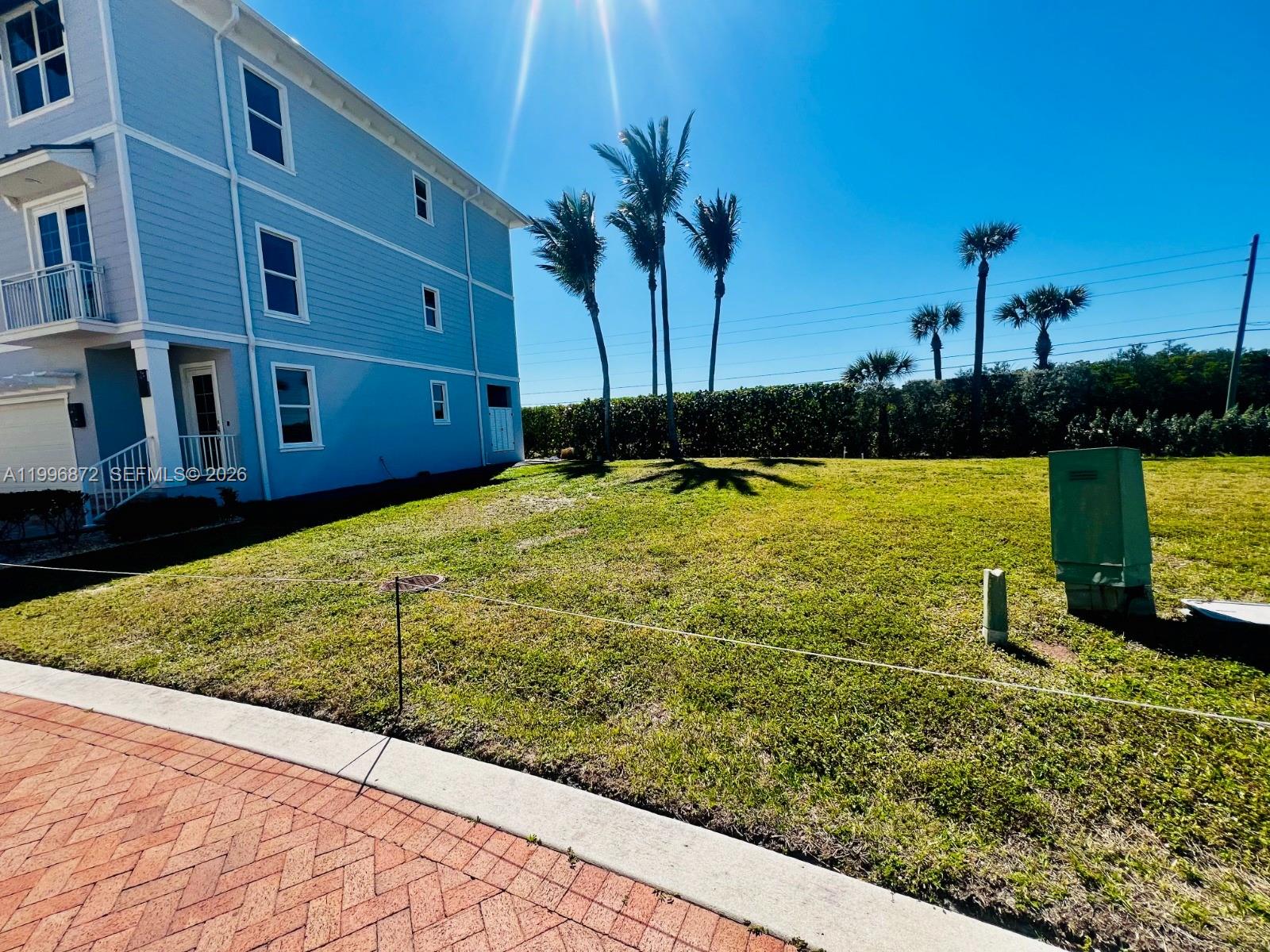 A light blue multi-story building stands next to a grassy yard with palm trees — 4803 Watersong Way, Fort Pierce FL 34949, FORT PIERCE, FL
