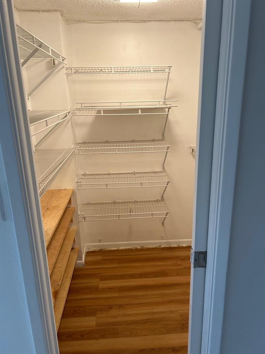 A walk-in pantry features wire shelving on the back wall and wooden shelves on the side — 2661 S Course Drive # 703, Pompano Beach FL 33069, POMPANO BEACH, FL
