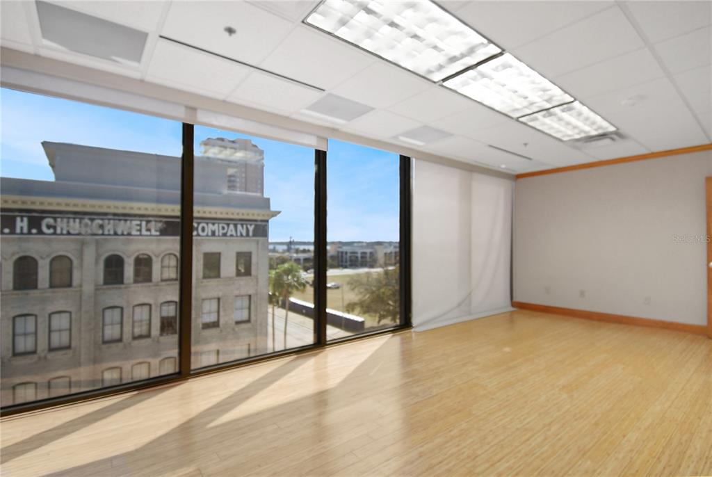 An empty office with light wood flooring, a drop ceiling, and large windows overlooking a building — 233 E BAY STREET UNIT 615, JACKSONVILLE, FL