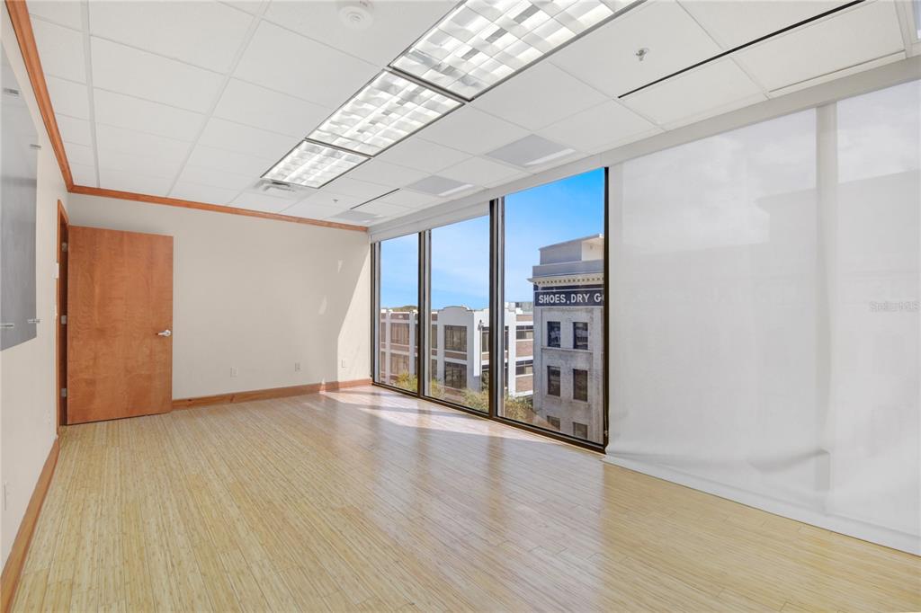 An empty office with light wood flooring, a drop ceiling, and large windows overlooking buildings — 233 E BAY STREET UNIT 615, JACKSONVILLE, FL
