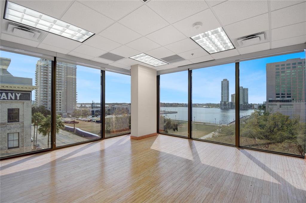 An empty office space features floor-to-ceiling windows, light wood flooring, and a drop ceiling — 233 E BAY STREET UNIT 615, JACKSONVILLE, FL