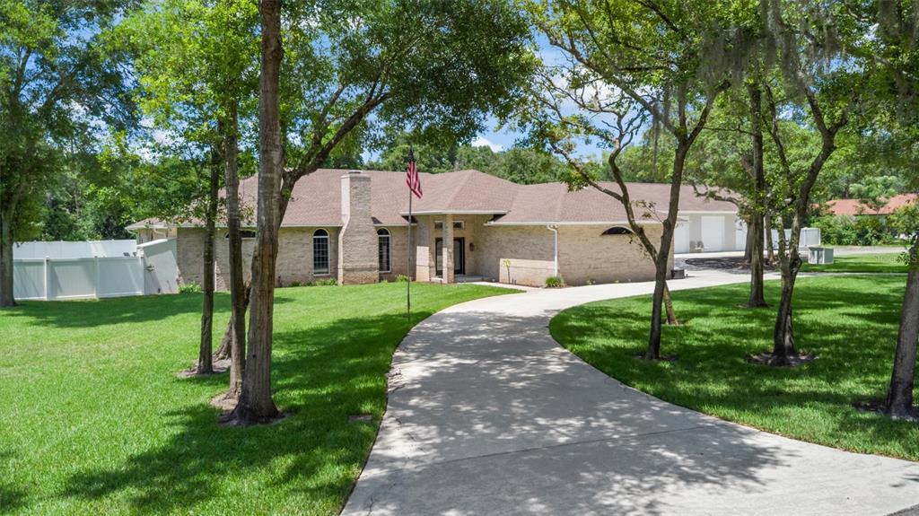 A single-story brick house with a concrete driveway and a large front lawn — 713 ERNEST DRIVE, PORT ORANGE, FL