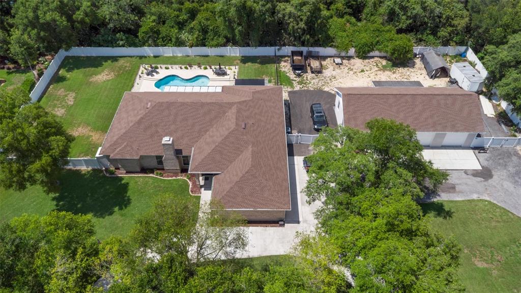 An aerial view shows a house with a pool, a detached garage, and large trees — 713 ERNEST DRIVE, PORT ORANGE, FL