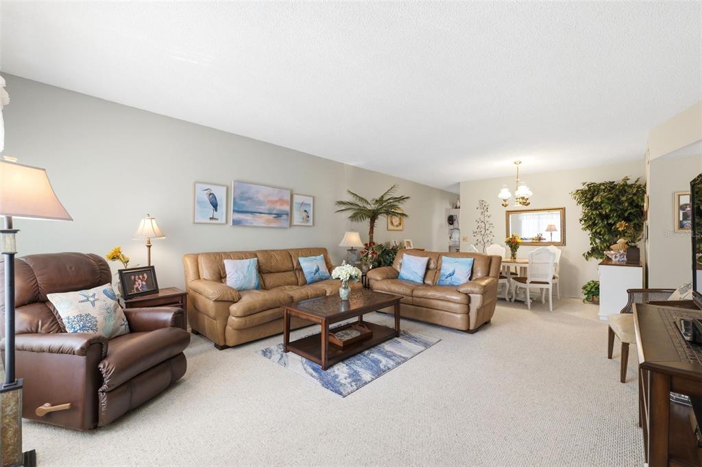 A living room features tan leather sofas, a brown recliner, and a dining area nearby — 2430 FLORENTINE WAY UNIT 58, CLEARWATER, FL
