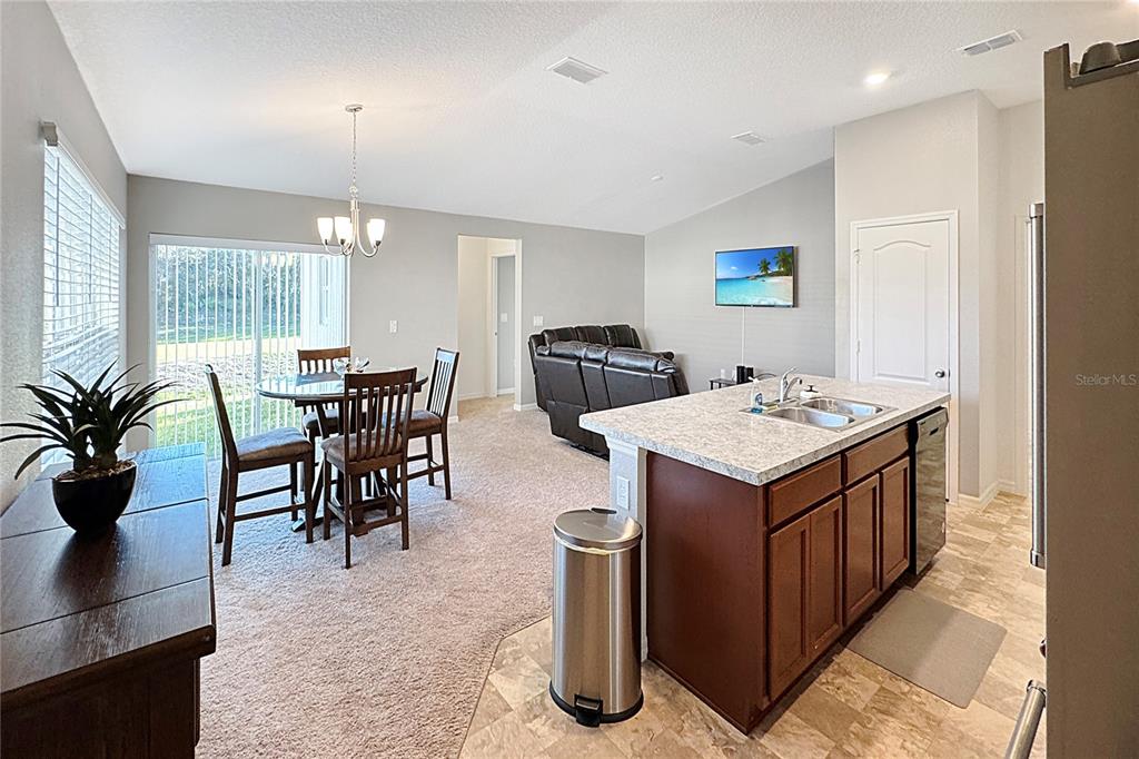 An open-concept kitchen with an island overlooks a dining area and a living room — 591 PRESERVE POINTE BOULEVARD, DAVENPORT, FL