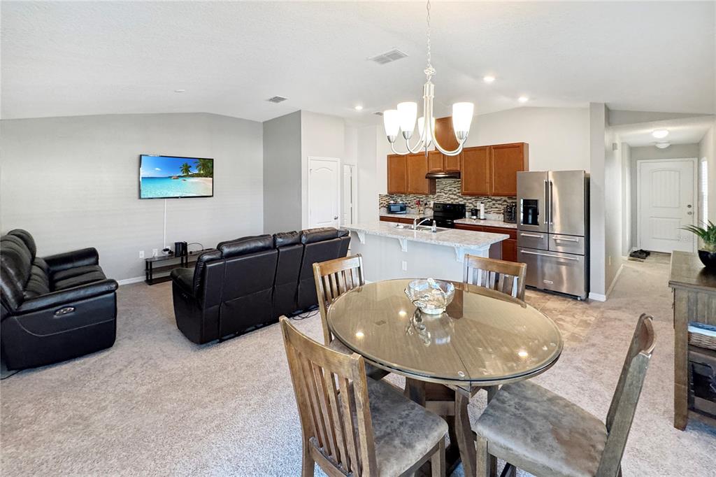 An open-concept living and dining area features a kitchen with wood cabinets and stainless appliances — 591 PRESERVE POINTE BOULEVARD, DAVENPORT, FL