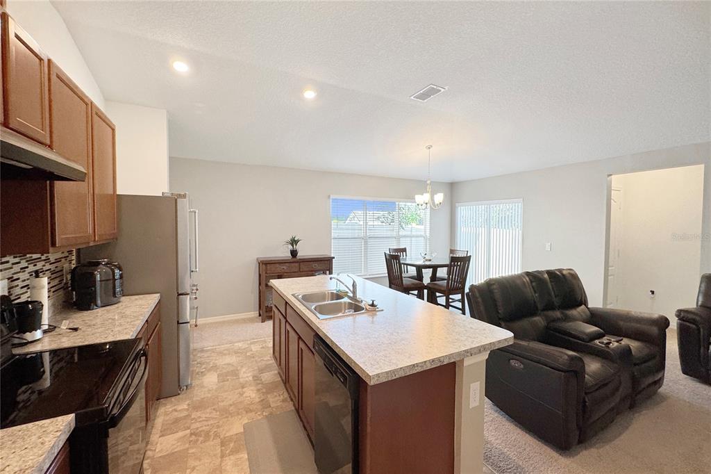 A kitchen with a center island and stainless steel appliances opens to a dining area — 591 PRESERVE POINTE BOULEVARD, DAVENPORT, FL