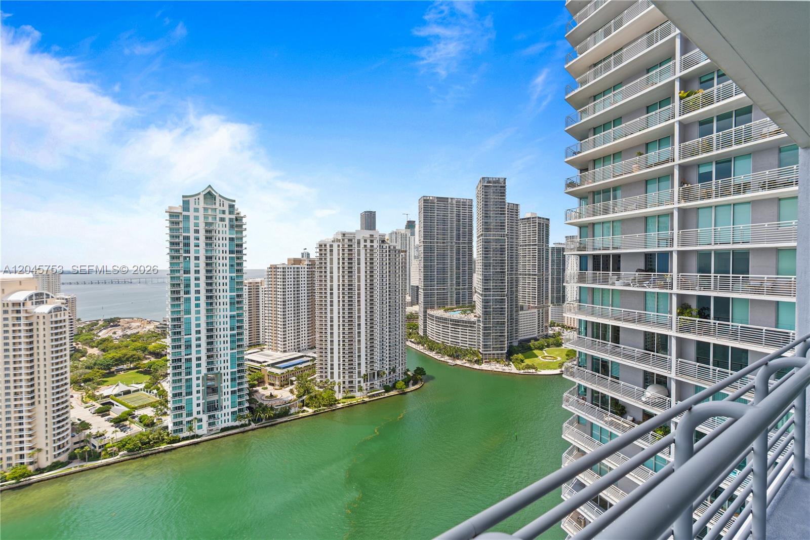 A high-angle view shows a balcony overlooking a river surrounded by tall city skyscrapers — 335 S Biscayne Blvd # 3503, Miami FL 33131, MIAMI, FL