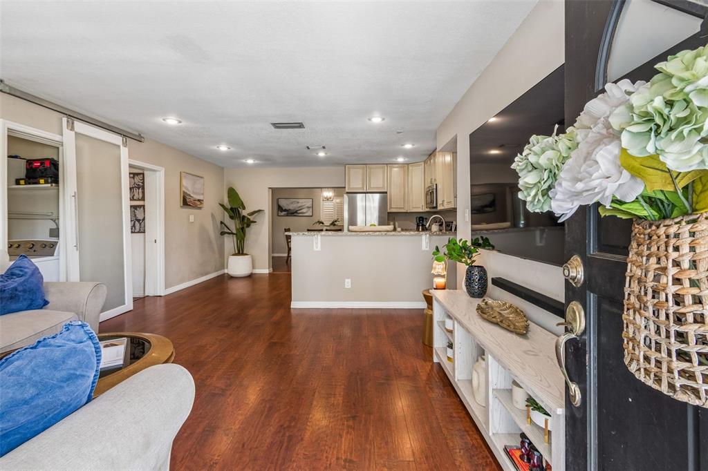 A living room with wood flooring opens to a kitchen featuring a breakfast bar — 11307 N BOULEVARD, TAMPA, FL
