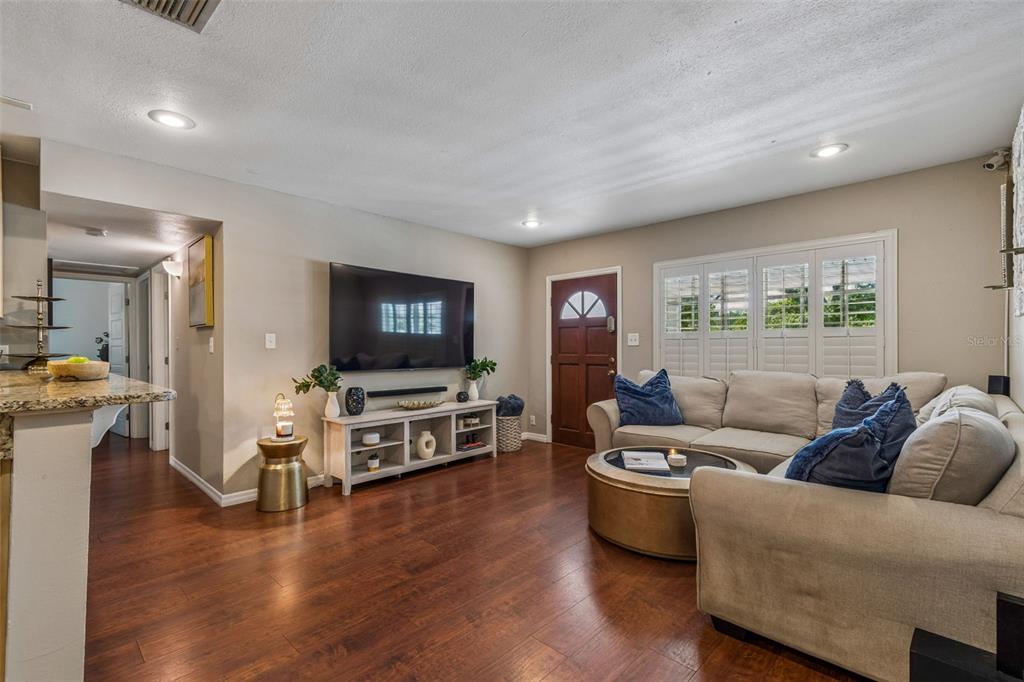A living room features hardwood floors, a wall-mounted television, a white media console, and sofa — 11307 N BOULEVARD, TAMPA, FL