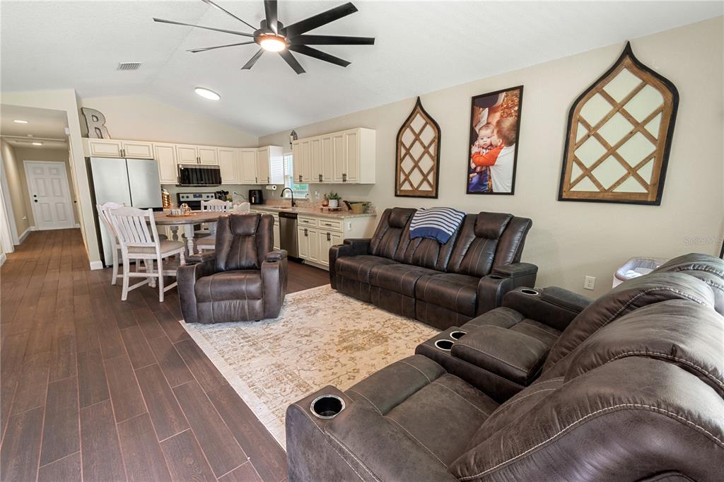 A living room with dark leather furniture, a patterned rug, and an open-concept kitchen — 765 S DUDLEY AVENUE, BARTOW, FL