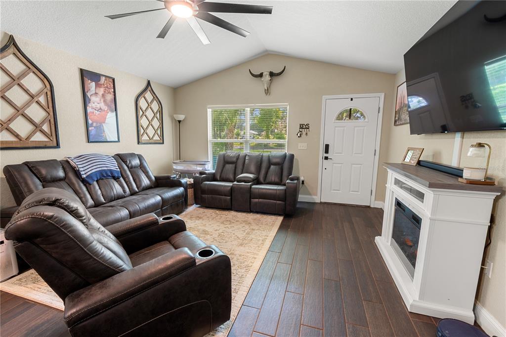 A living room features dark leather recliners, a fireplace, a television, and wood-look flooring — 765 S DUDLEY AVENUE, BARTOW, FL