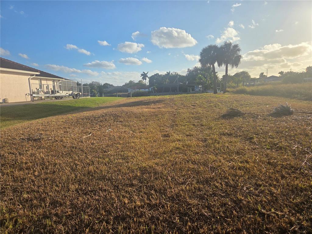 A vacant, grassy residential lot sits adjacent to a house with a screened-in patio — 13429 MARQUETTE BOULEVARD, FORT MYERS, FL
