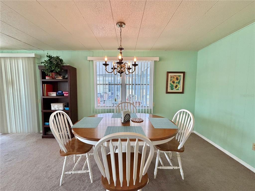 A dining room features a round wooden table, white chairs, and a chandelier — 114 ASPEN CIRCLE, LEESBURG, FL
