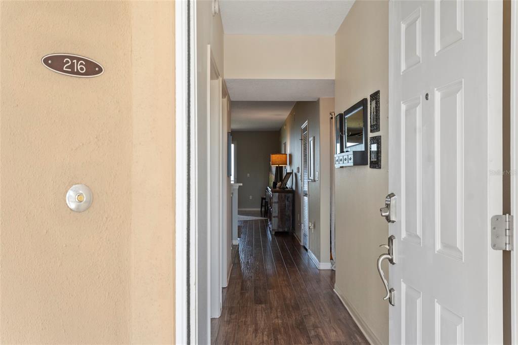 A view from an open doorway looking down a hallway with wood-look flooring — 80 SURFVIEW DRIVE UNIT 216, PALM COAST, FL