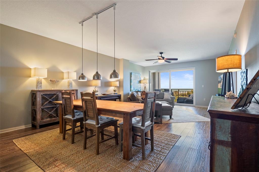 A dining area with a wooden table and pendant lights opens into a living room — 80 SURFVIEW DRIVE UNIT 216, PALM COAST, FL