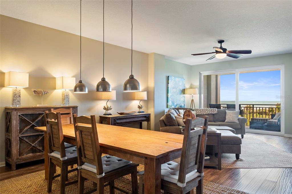 A dining area with a wooden table and pendant lights opens to a living room — 80 SURFVIEW DRIVE UNIT 216, PALM COAST, FL