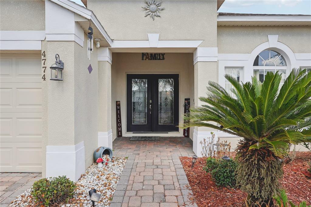 The exterior of a house features a brick walkway leading to a double front door — 4774 CUMBRIAN LAKES DRIVE, KISSIMMEE, FL